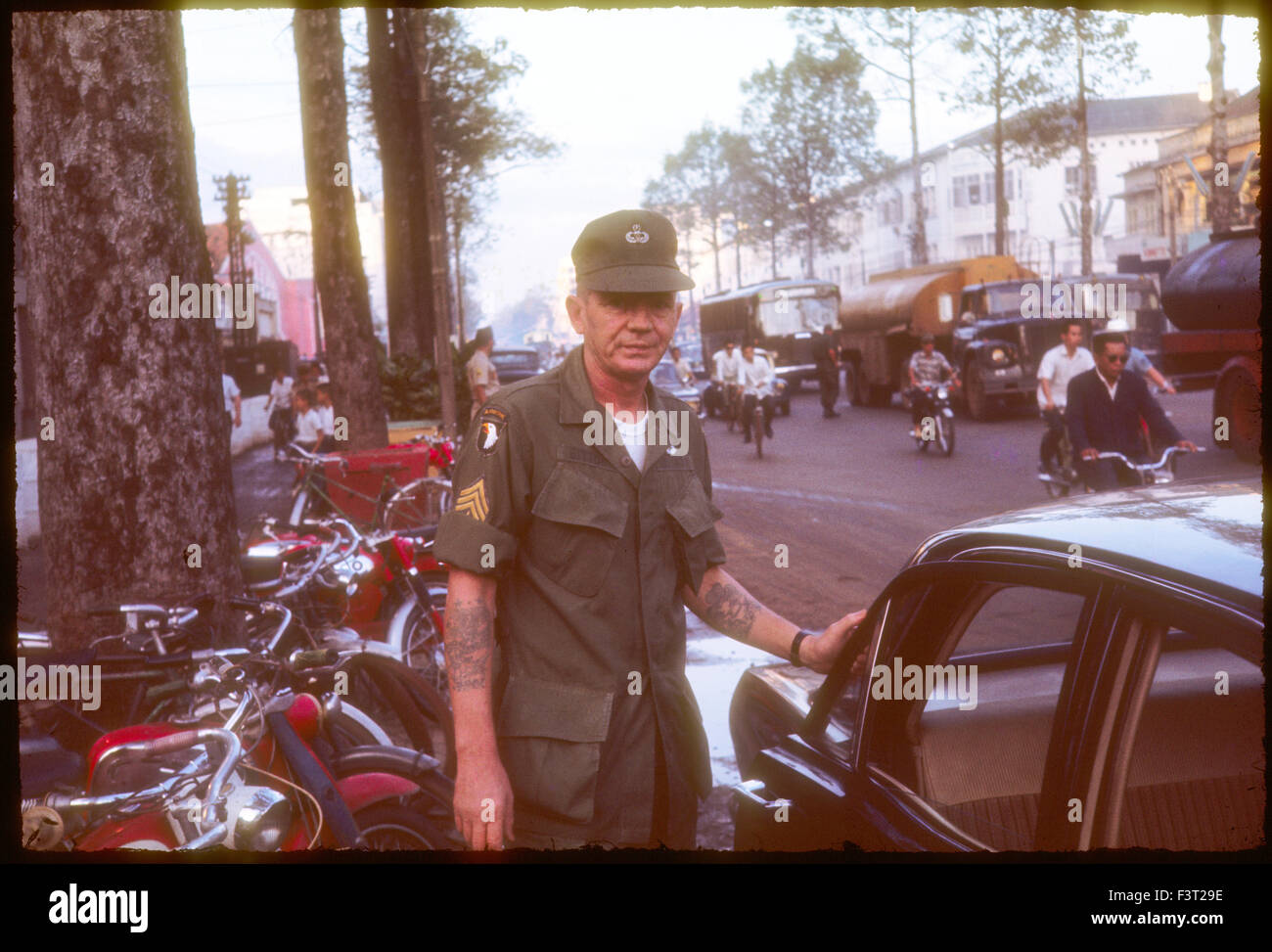 Il sergente indossando un patch dal 101st Airborne Division, e saltare le ali, per indicare un precedente tour, sorge vicino a una strada trafficata a Saigon durante la Guerra del Vietnam. Foto Stock