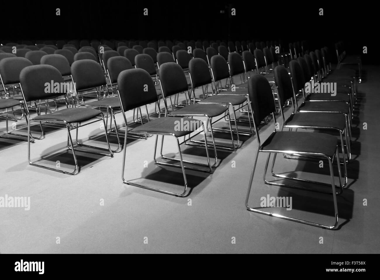 File di sedie vuote preparato per un evento al coperto Foto Stock