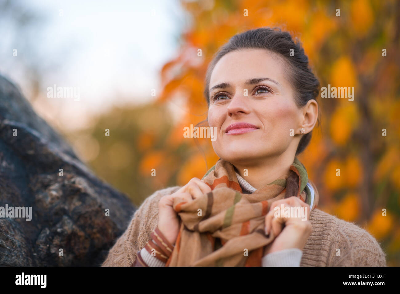 Ritratto di giovane i capelli castani donna in serata in autunno park premurosamente cercando riposo Foto Stock