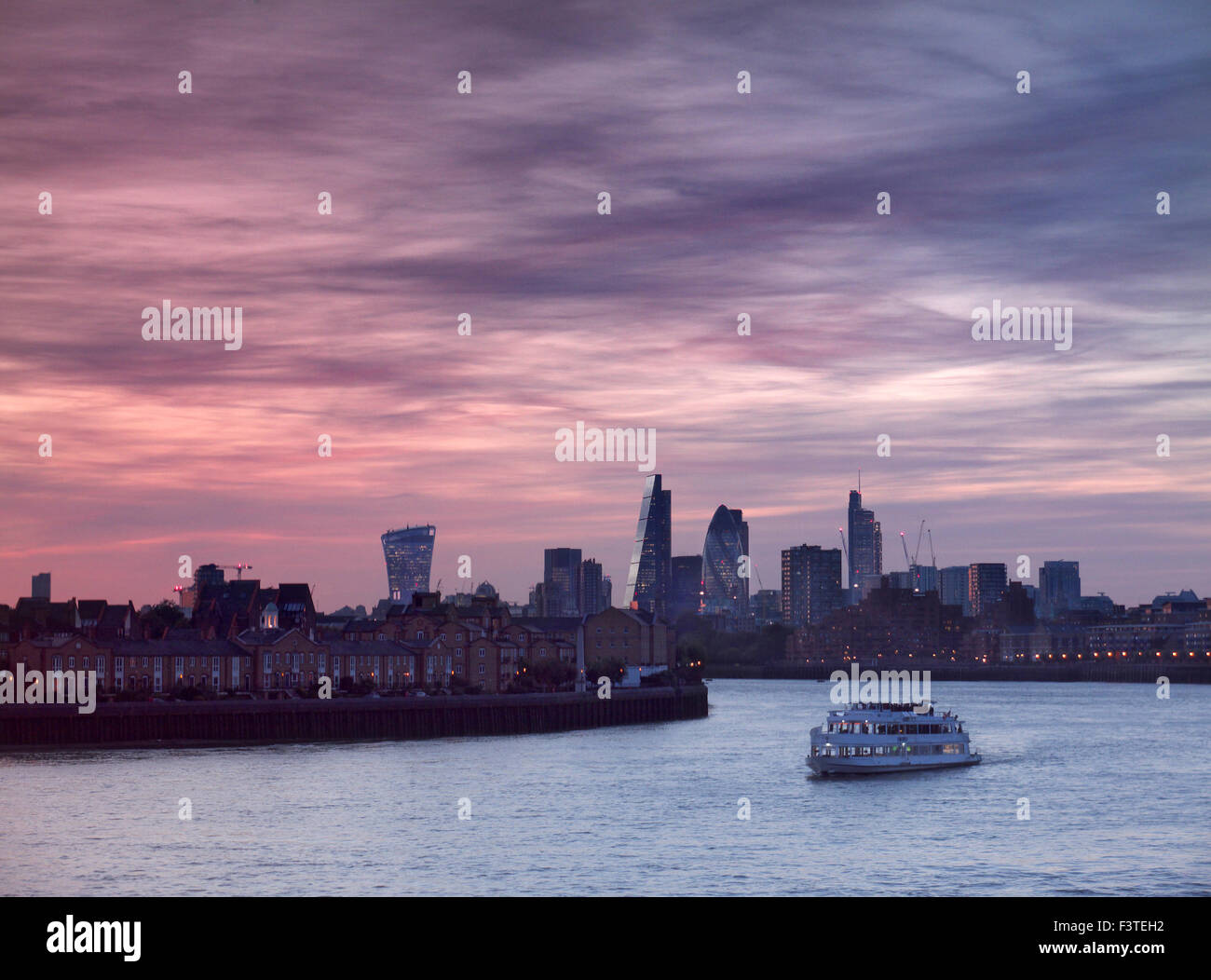 London financial city centre London visto dal Canary Wharf con una crociera sul fiume barca in primo piano al tramonto London EC1 Foto Stock