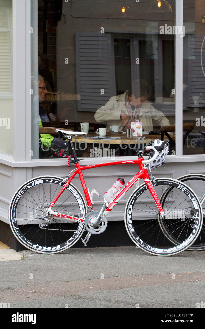 Un elegante rosa / rosso Lapierre bicicletta da strada appoggiata contro la parte anteriore di un coffee shop Foto Stock