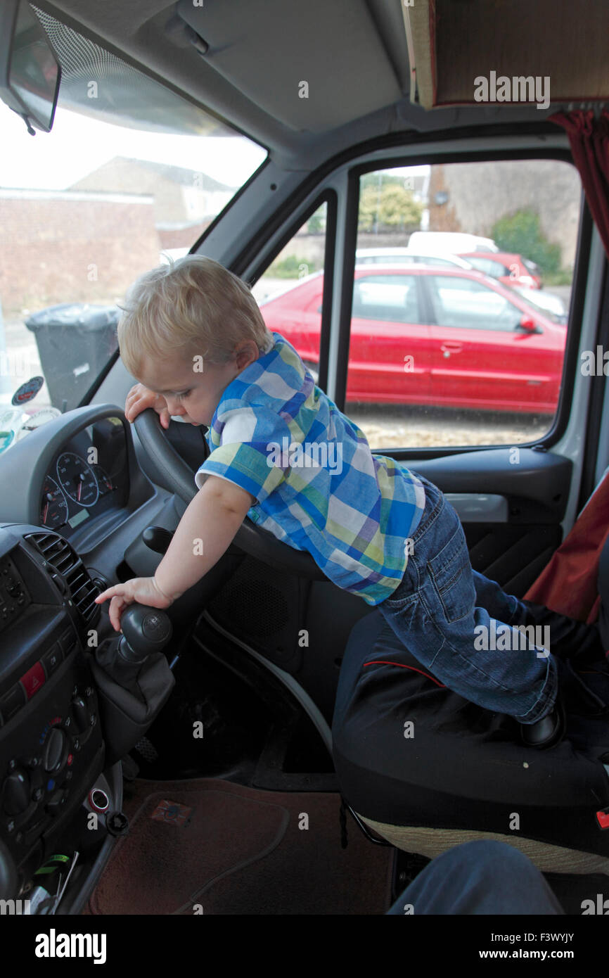 Il Toddler cercando di operete leva del cambio nel motorhome stazionaria Foto Stock