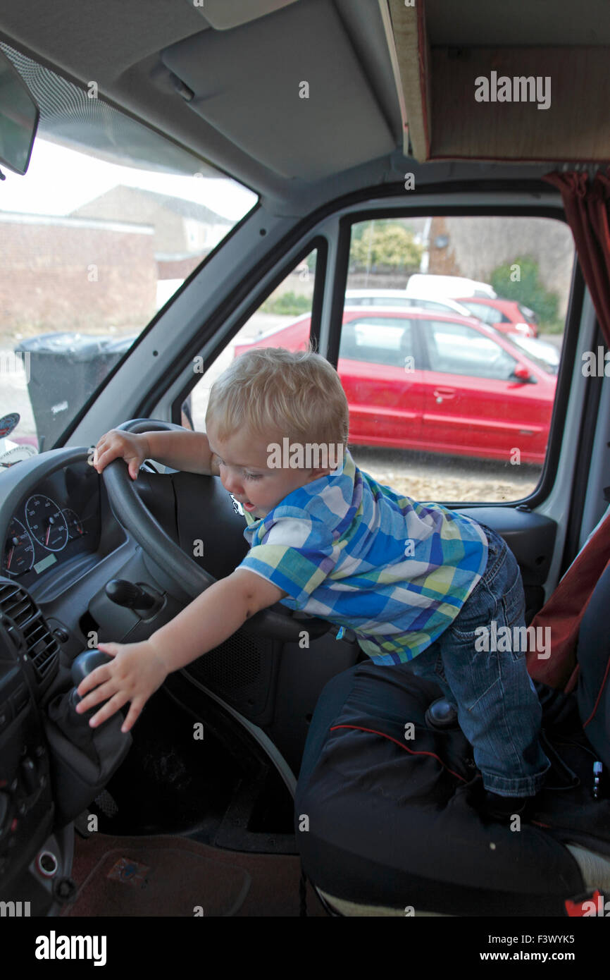 Il Toddler cercando di lavorare con la leva del cambio in camper stazionaria Foto Stock