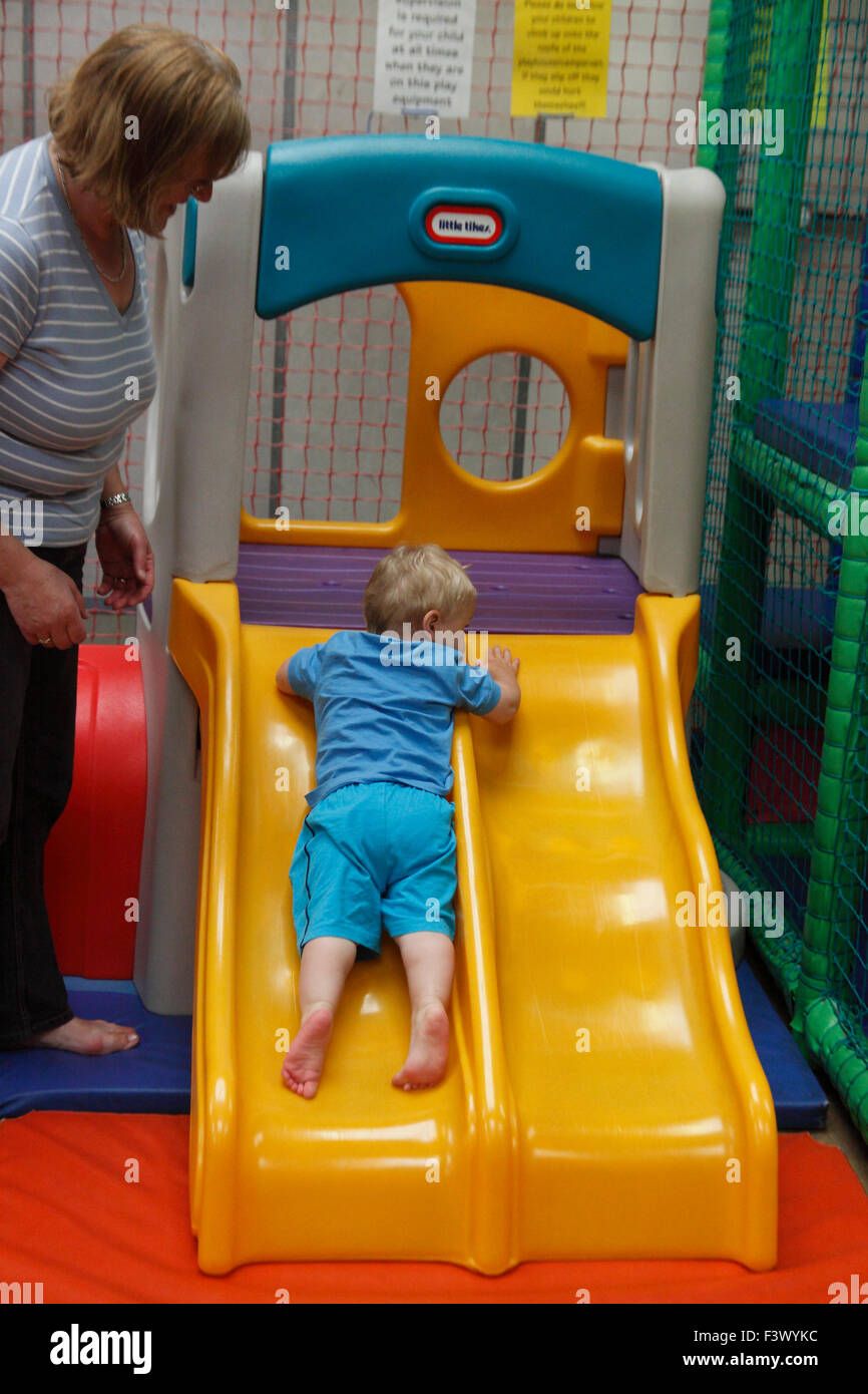 Bambino a imparare a utilizzare scorrere sotto la supervisione sul undercover area di gioco Foto Stock