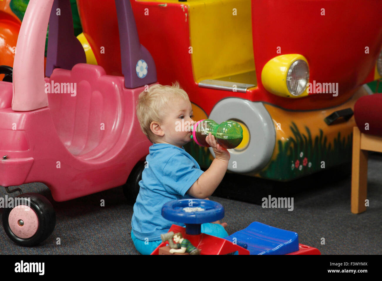 Bambino si ferma per un drink durante la sessione di gioco Foto Stock