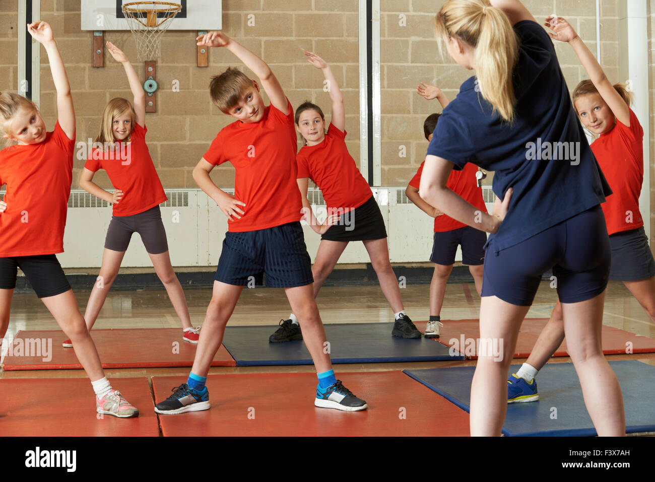 Tenendo l'insegnante di classe di esercizio nella palestra della scuola Foto Stock