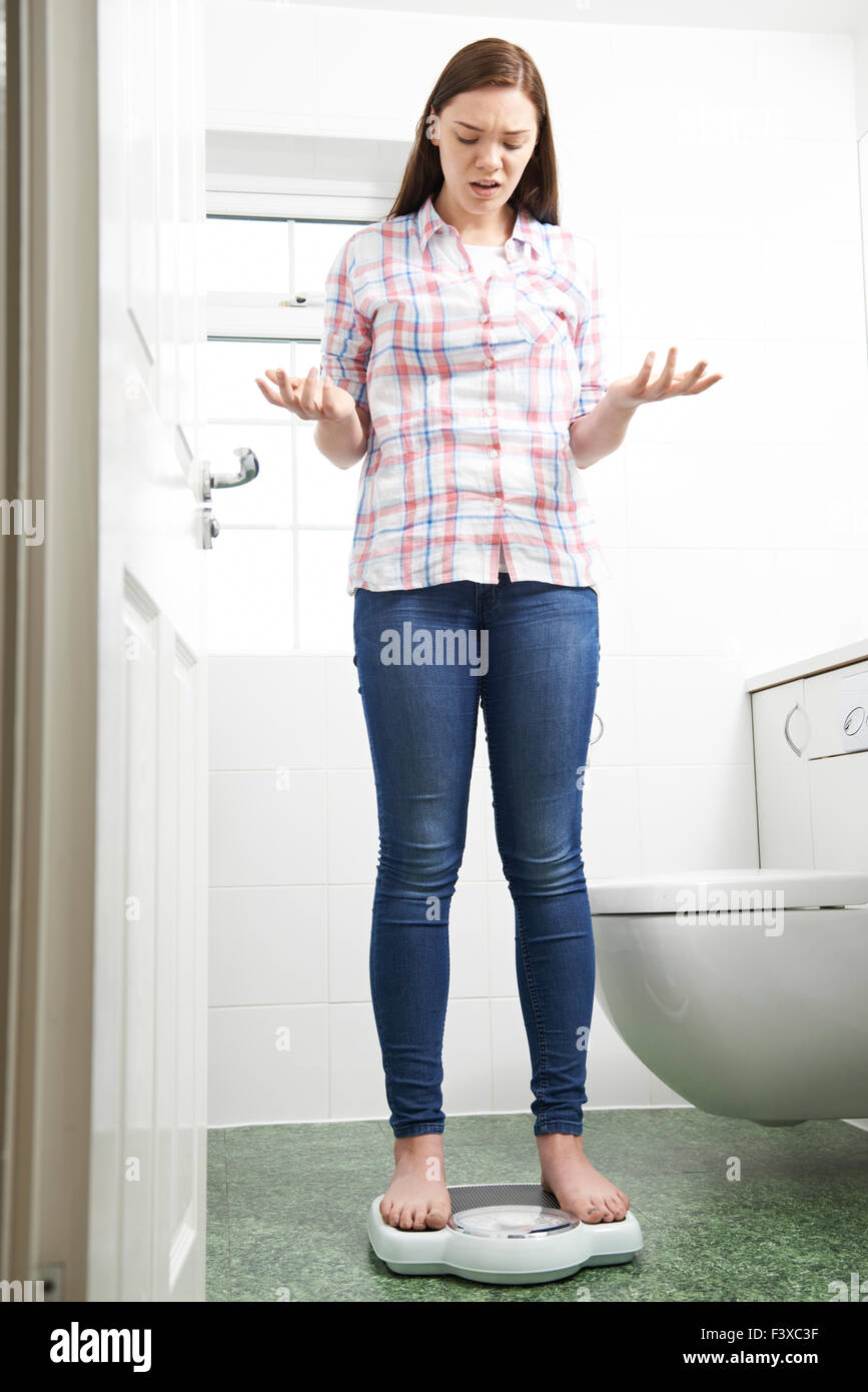 Infelice ragazza adolescente permanente sulla bilancia da bagno Foto Stock