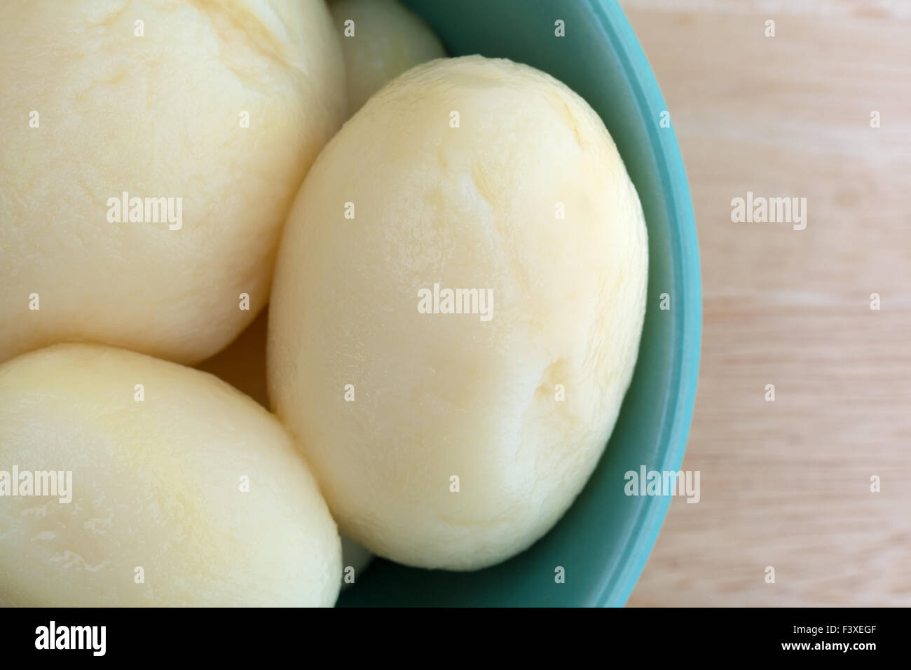 Top vista ravvicinata di una ciotola riempita con tutta la patate bianche su una tavola di legno top illuminato con luce naturale. Foto Stock