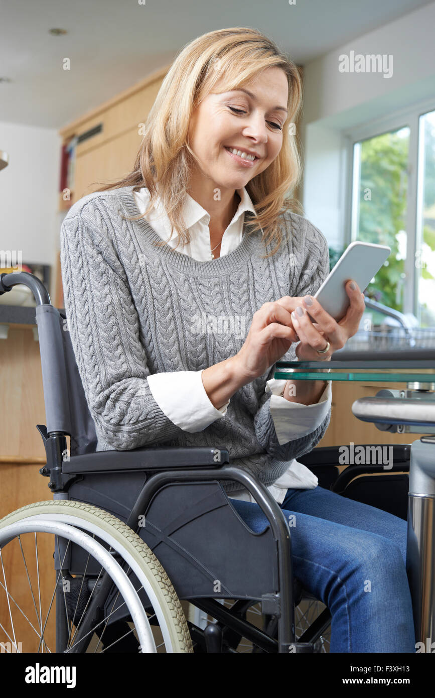 Donna disabile in carrozzella sms sul cellulare a casa Foto Stock