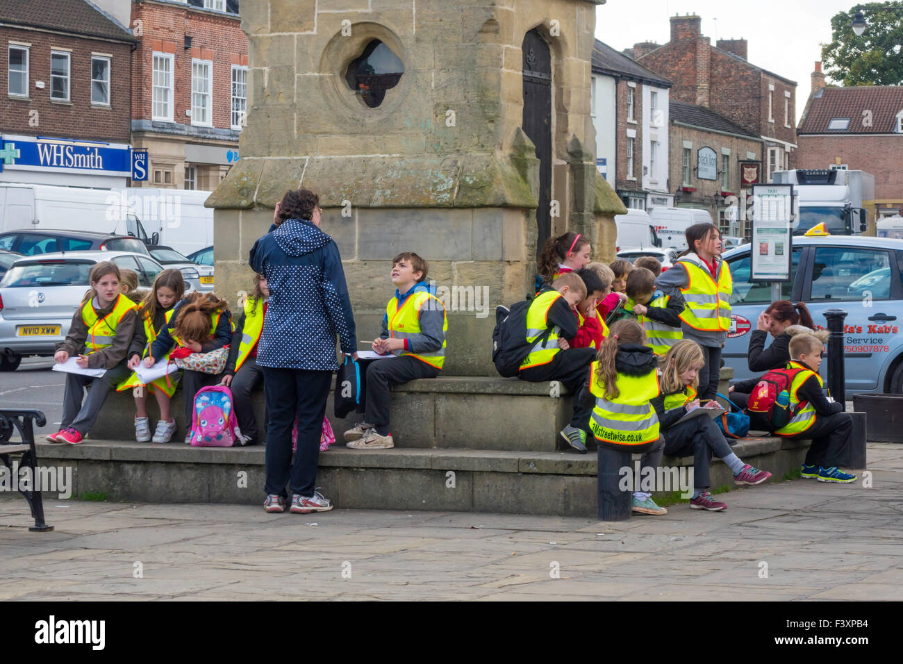 Un gruppo di bambini e insegnanti di una scuola gita presso la piazza del mercato Thirsk North Yorkshire Foto Stock