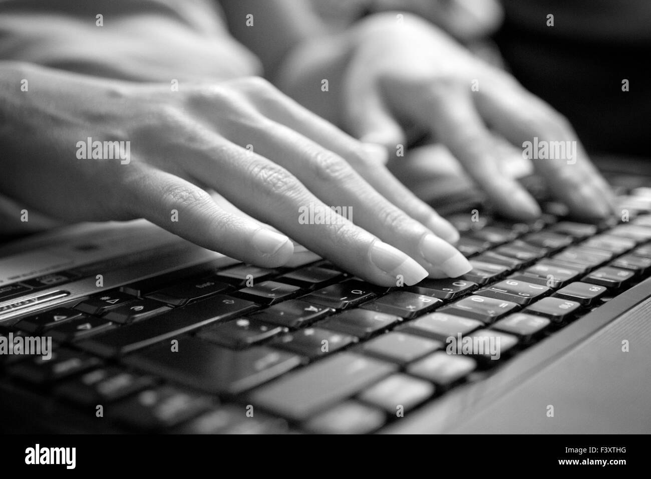 Mani lavorando su una tastiera in bianco nero Foto Stock