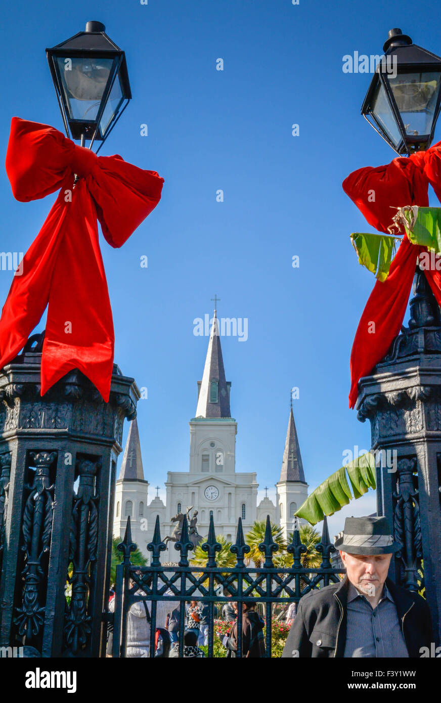 L'uomo con il cappello di fronte degli antichi lampioni con red Holiday archi, Cattedrale di San Louis, Jackson Square New Orleans, LA Foto Stock