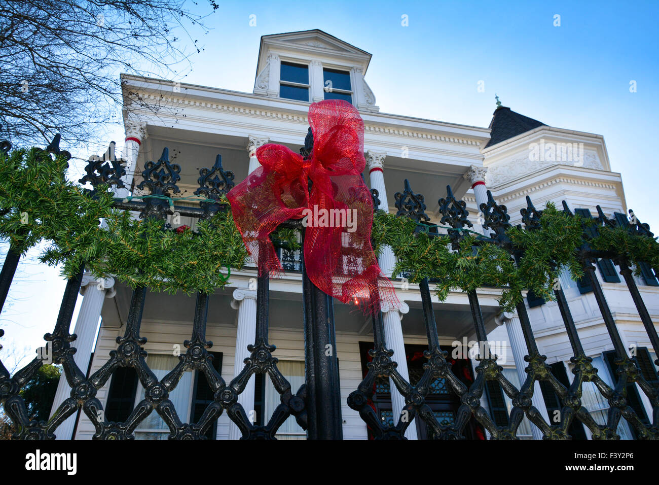 Nastro rosso legato attorno nero ferro battuto recinzione in parte anteriore della storica casa coloniale nel giardino del Distretto di New Orleans, LA Foto Stock