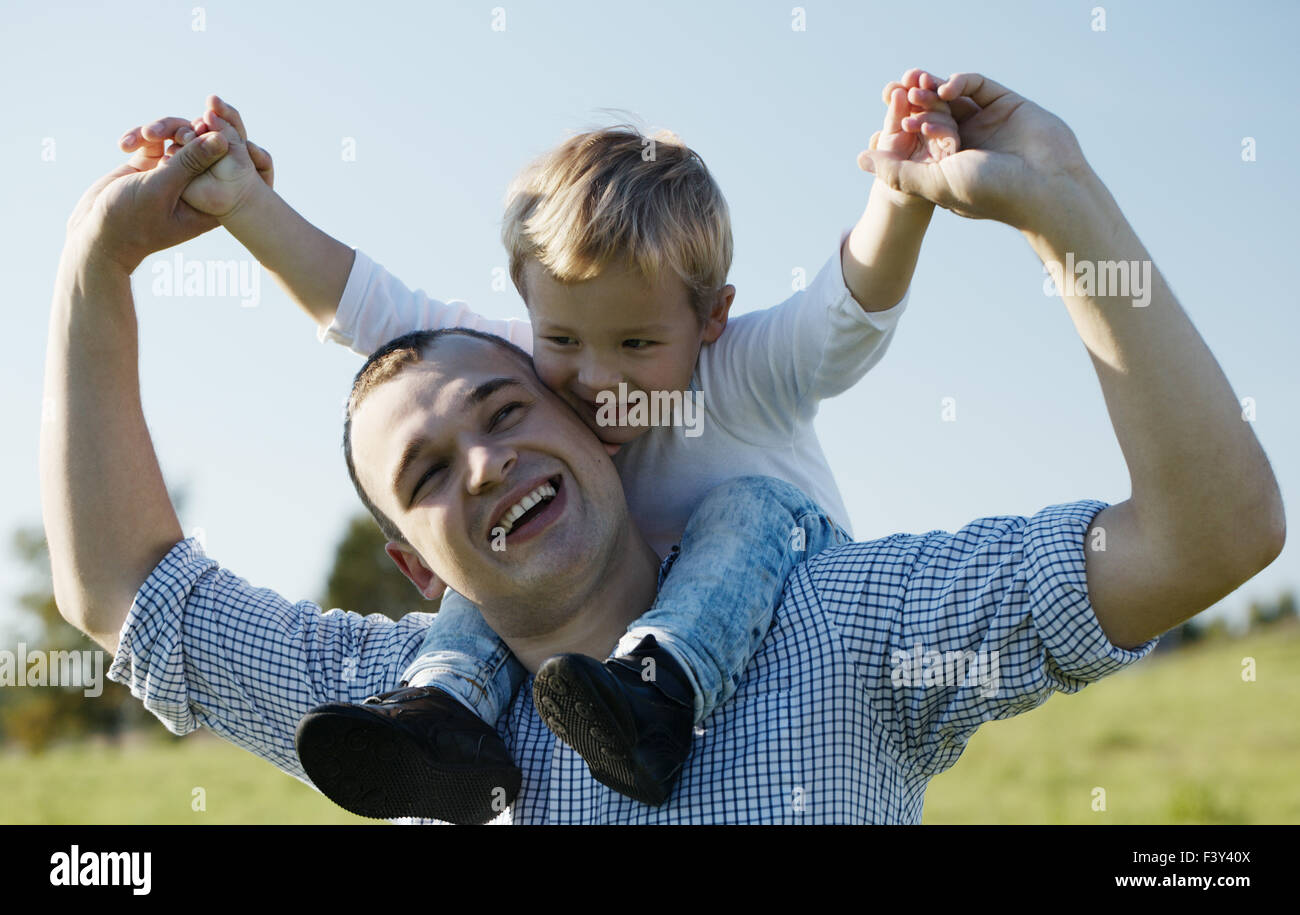 Papà dando il suo giovane figlio un piggy back ride Foto Stock