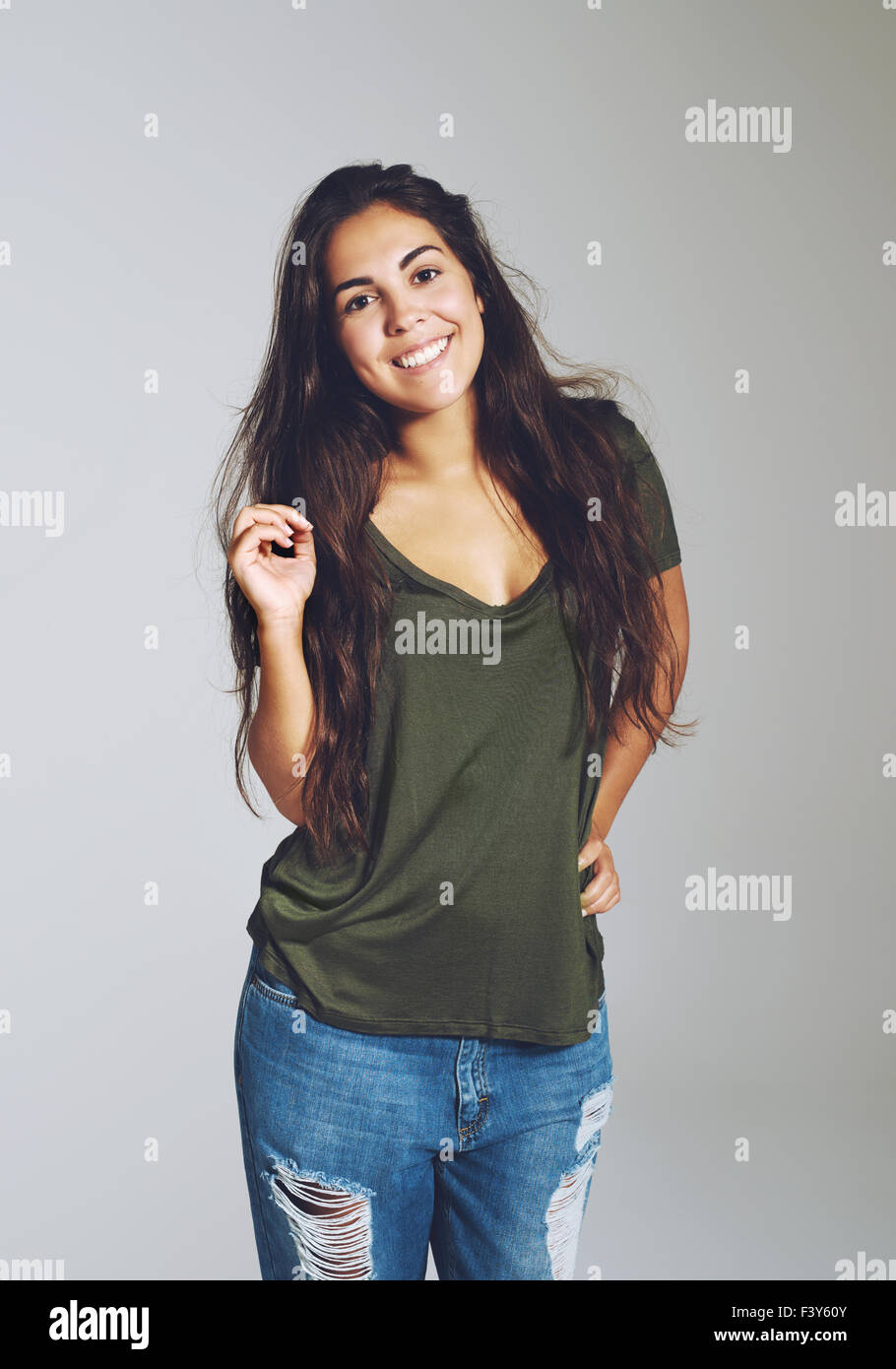 Bella attraente giovane donna con un caldo sorriso amichevole indossando ragged designer jeans e una t-shirt casual in piedi guardando Foto Stock