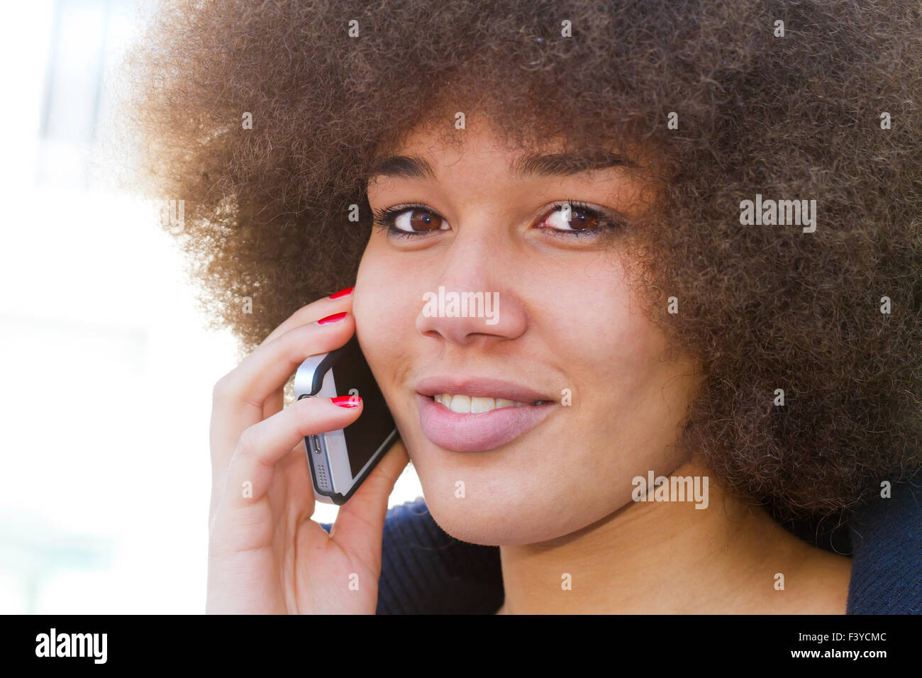 African American donna con capelli crespi acconciatura afro con smart phone Foto Stock