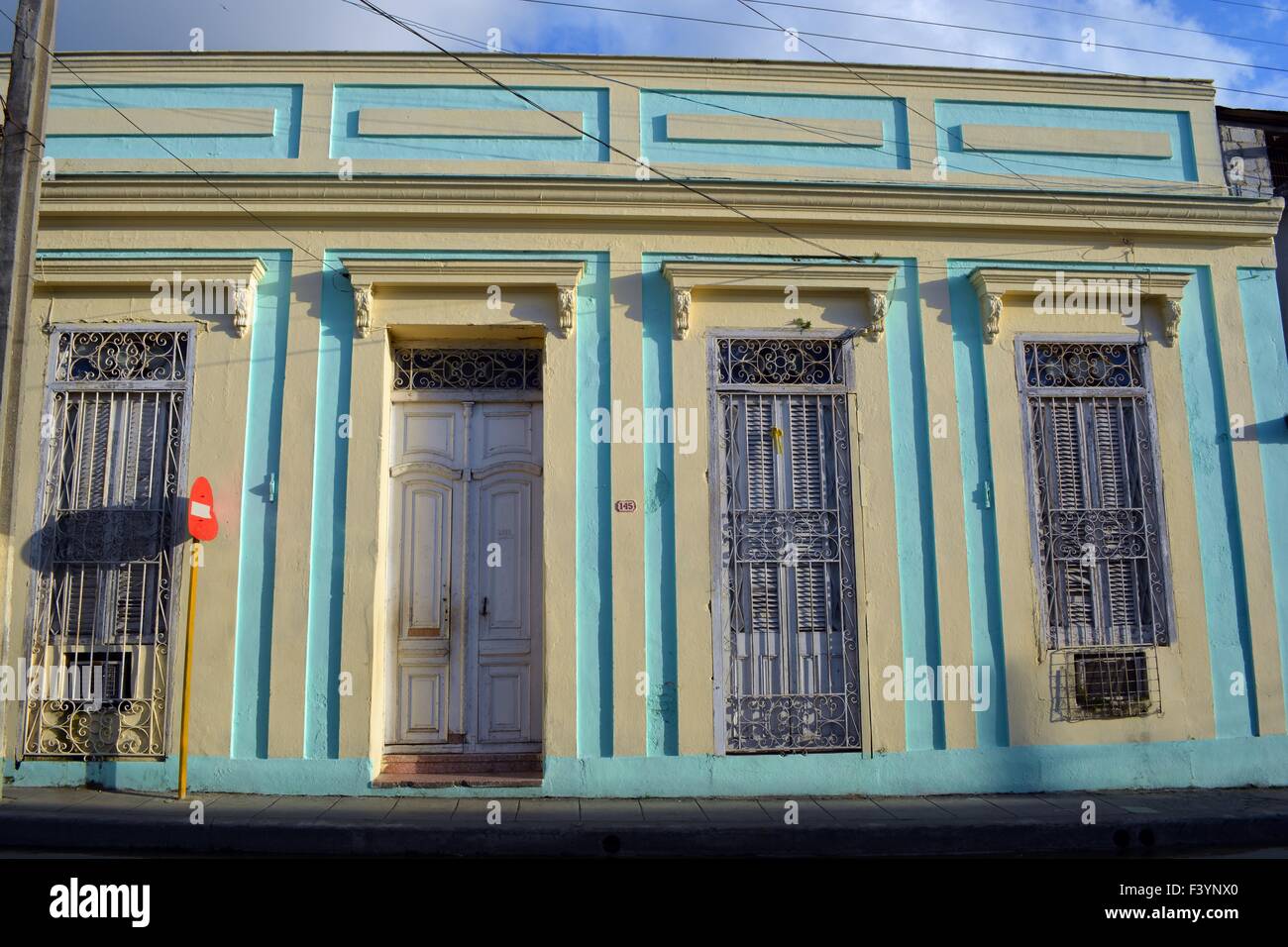 Turchese pastello giallo e la facciata del vecchio edificio coloniale, Santa Clara, Cuba con finestre a gabbia, porta bianca e persiane Foto Stock