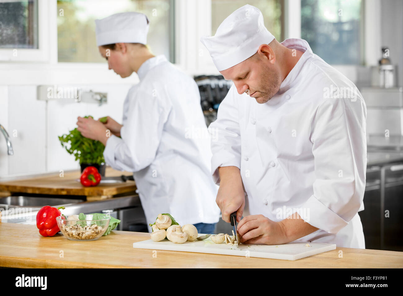 Due chef professionisti preparare verdure in cucina grande Foto Stock
