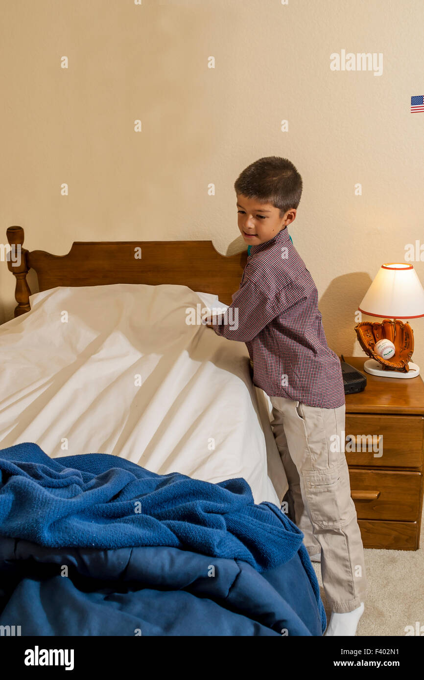 Tidy 7-10 anni di età giovane coreano/American boy rendendo il suo letto.  Signor ©Myrleen Pearson Foto stock - Alamy