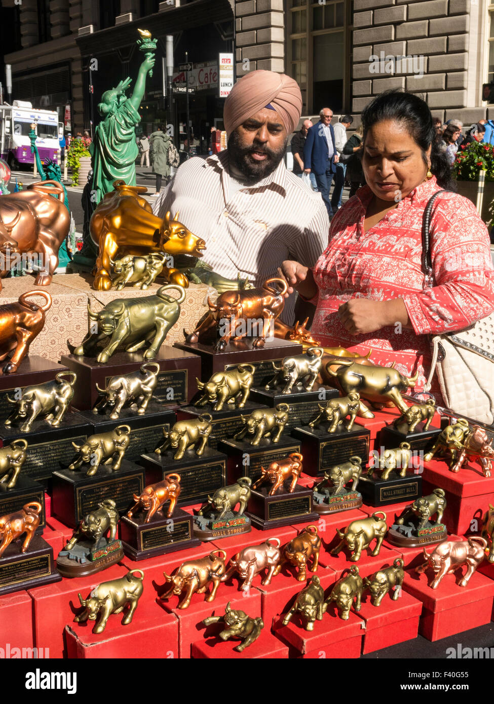 Turisti e stand di souvenir a Bull di ricarica la scultura a Bowling Green Park, NYC Foto Stock