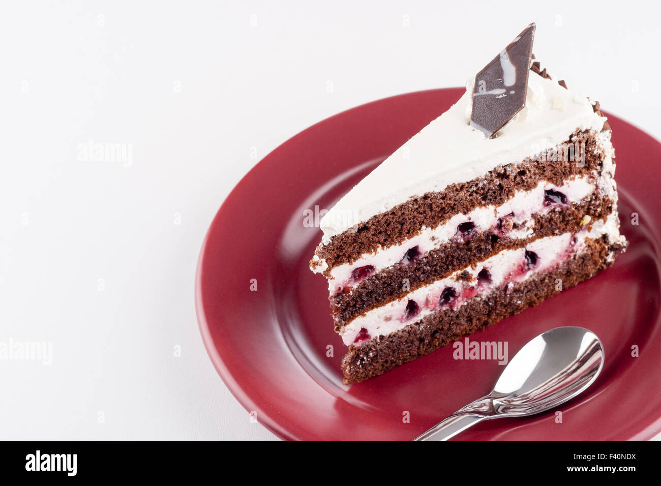Torta multistrato sulla piastra con cucchiaino Foto Stock