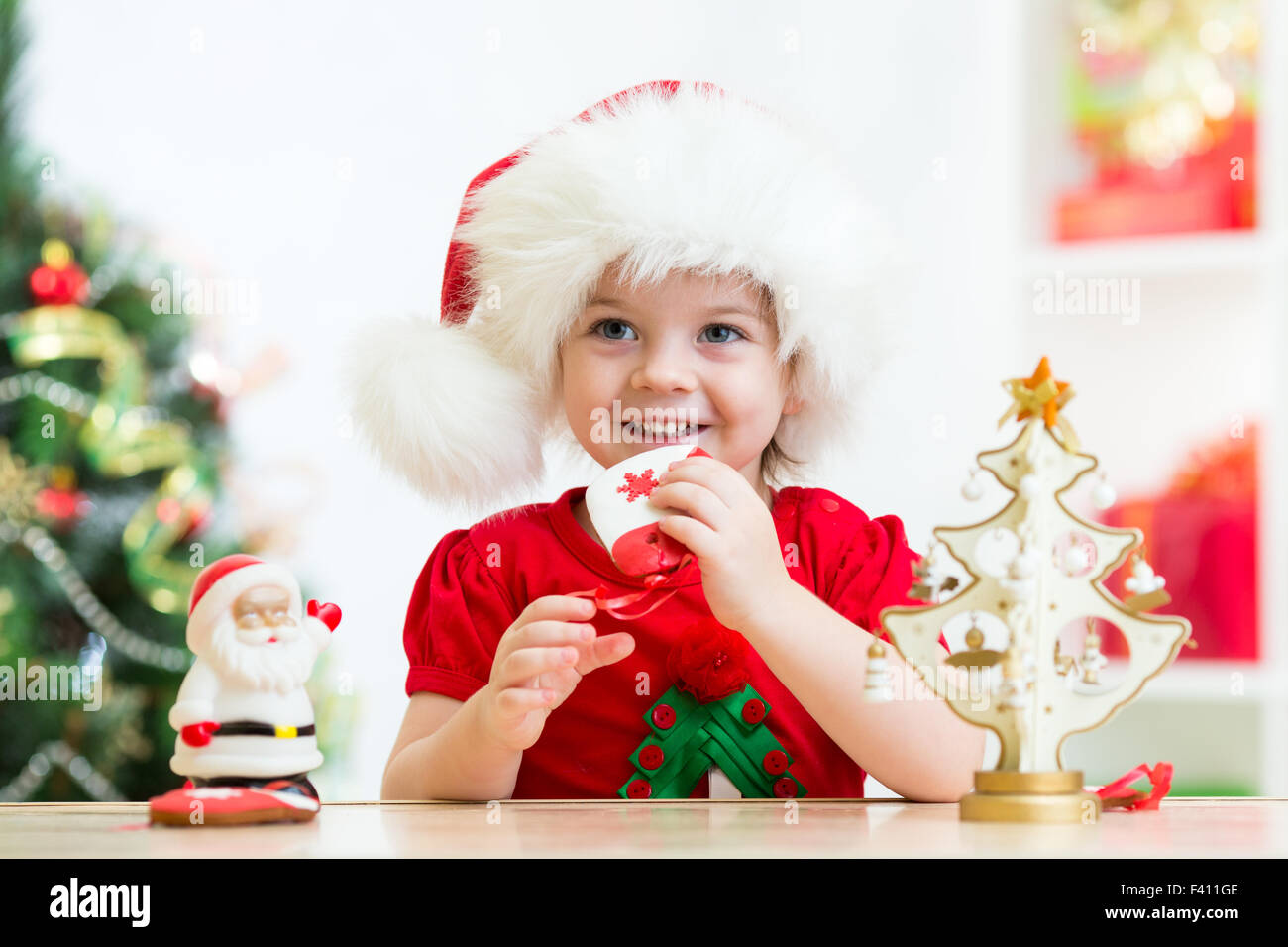 Bambina indossa un festoso Santa Red hat con biscotti di Natale Foto Stock