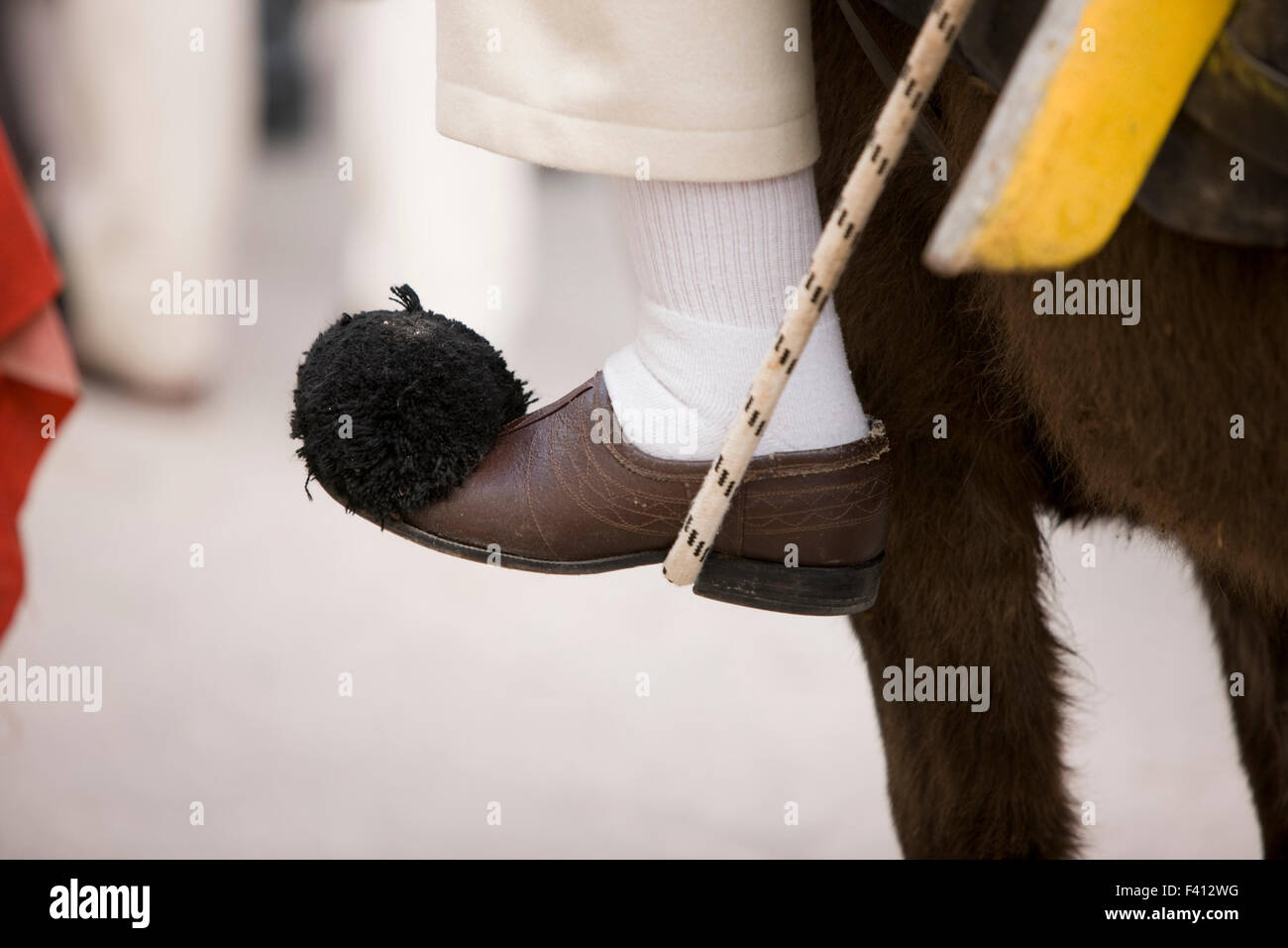 Primo piano dettaglio di un greco vlach indossando il tradizionale tsarouhi/ tsarouhia calzature, cavalcando un asino nella città di Tebe. La Grecia. Foto Stock