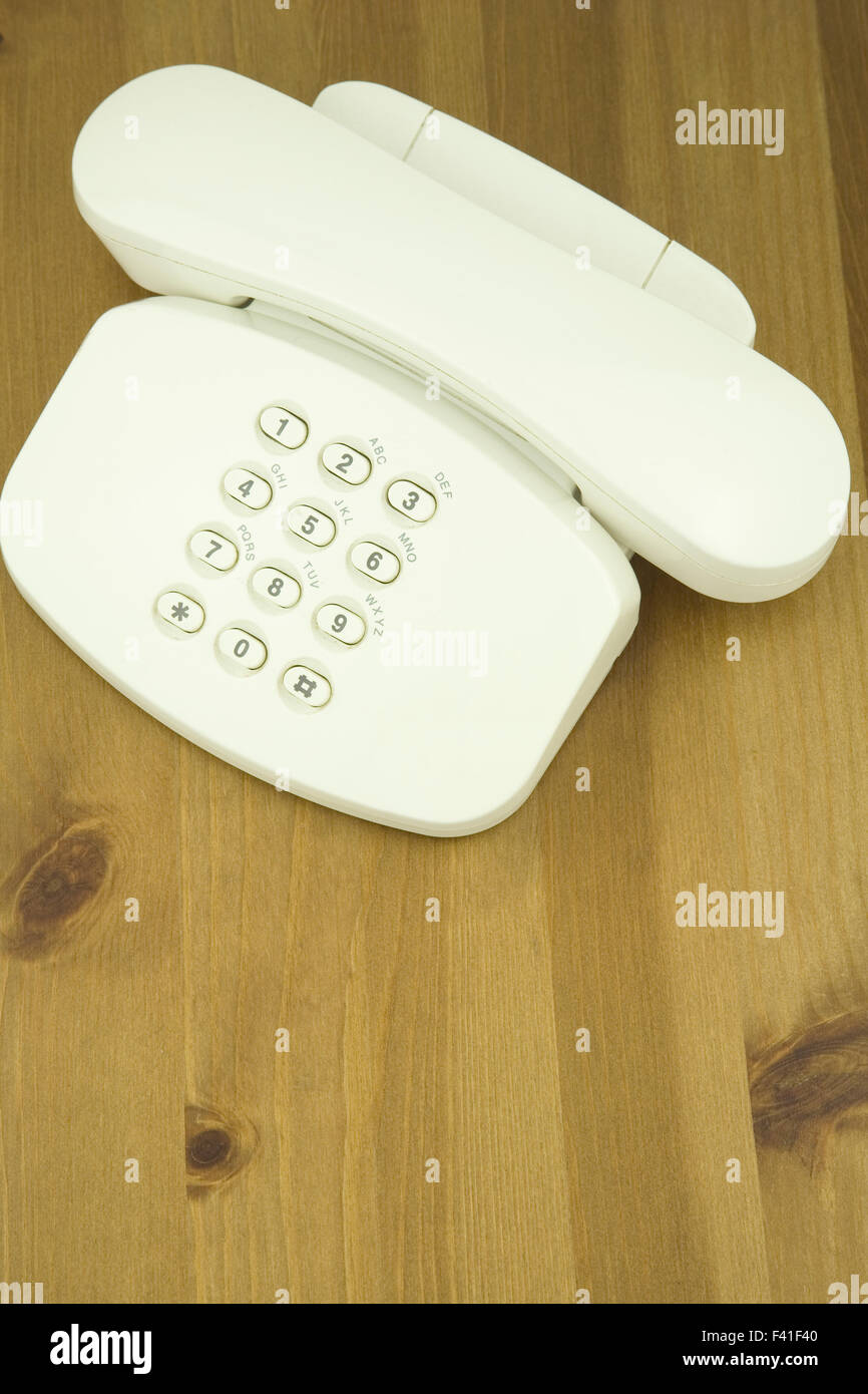 Vista in elevazione di un telefono bianco su un tavolo di legno, Foto Stock