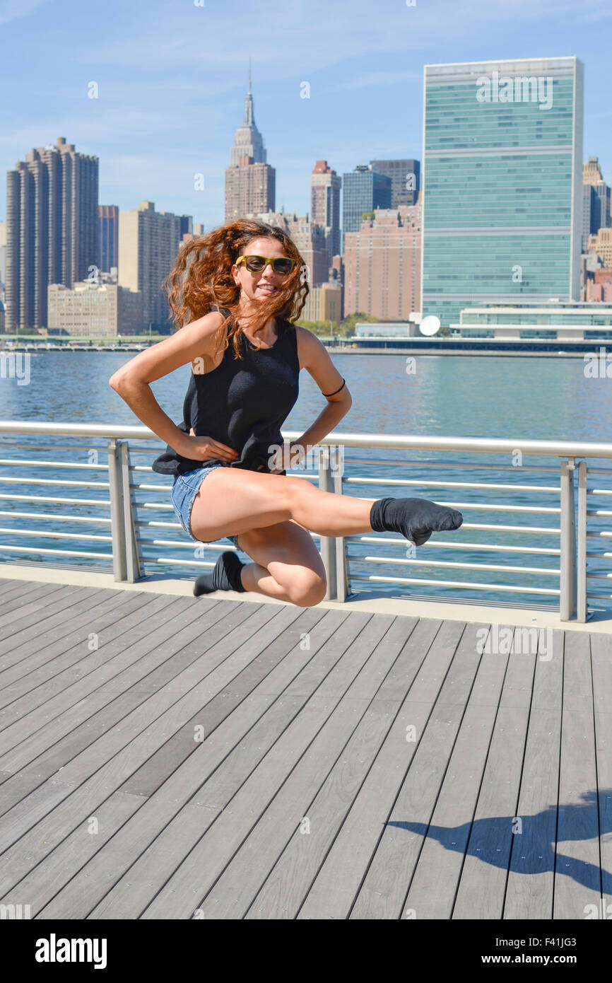 Ragazza di eseguire la danza irlandese "Birdie" salto contro vista di Manhattan Foto Stock