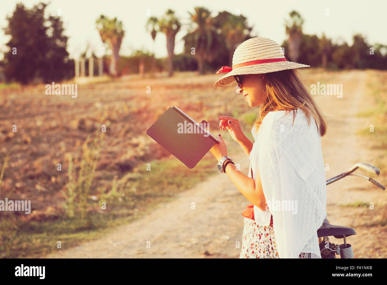 Giovane donna con la bici in campagna che lavorano su tablet Foto Stock