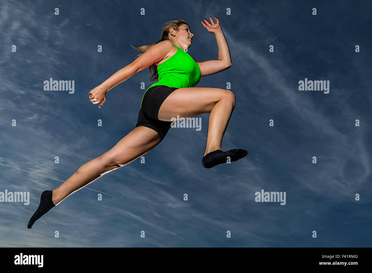 Giovane donna, 18 anni, saltando contro il cielo di sera Foto Stock