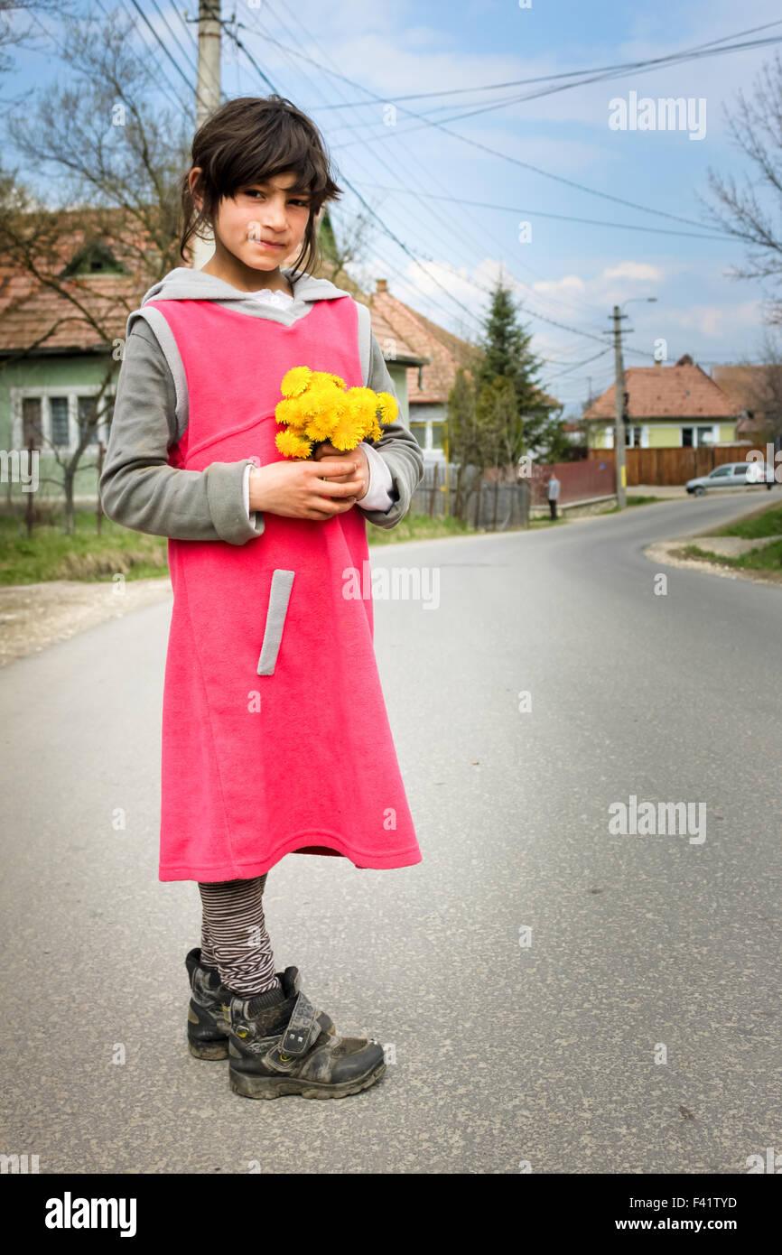 Un povero gipsy ragazza con fiori gialli pone per la fotocamera. Foto Stock