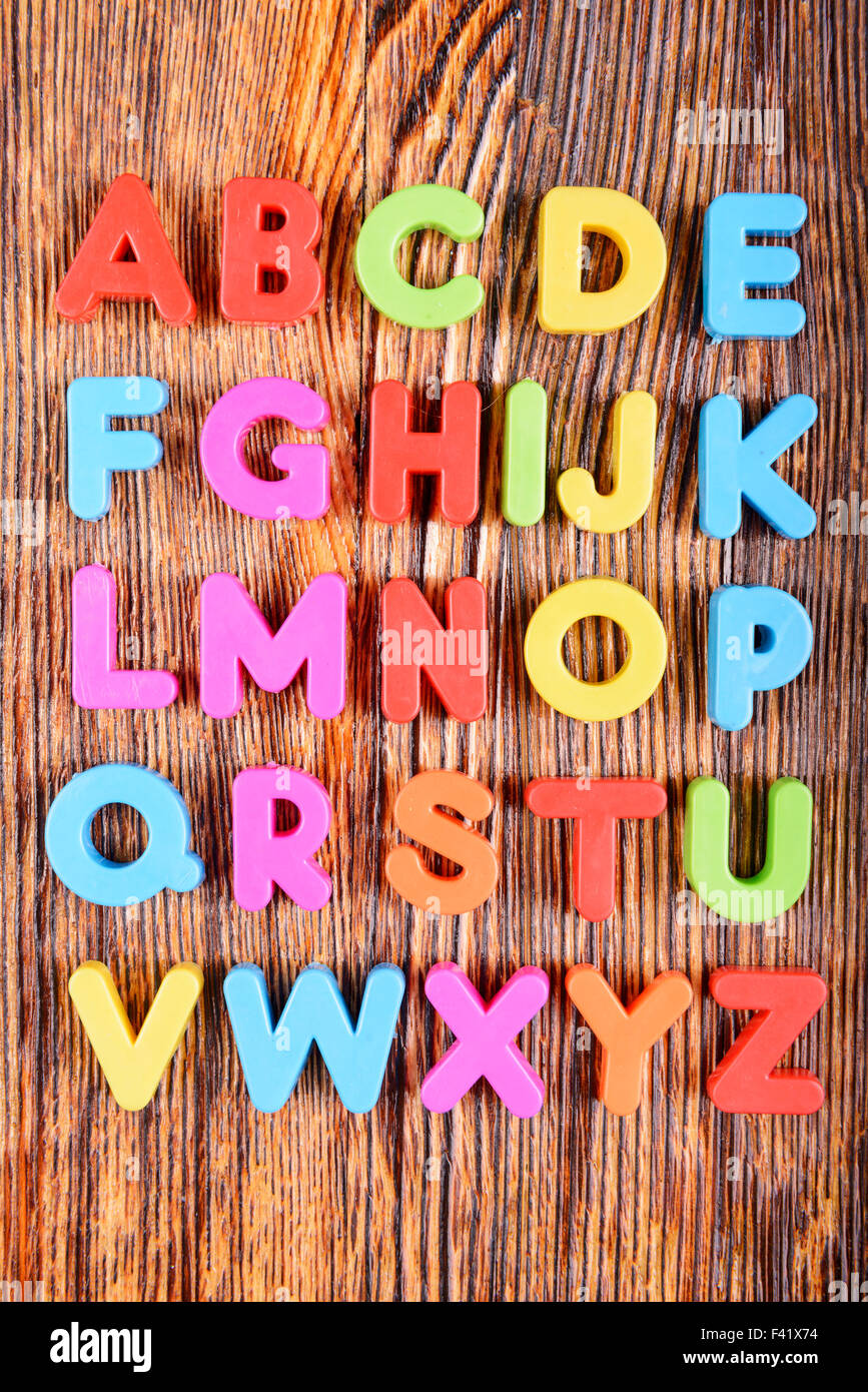 Composizione di materia plastica colorata alfabeto lettere sullo sfondo di legno Foto Stock