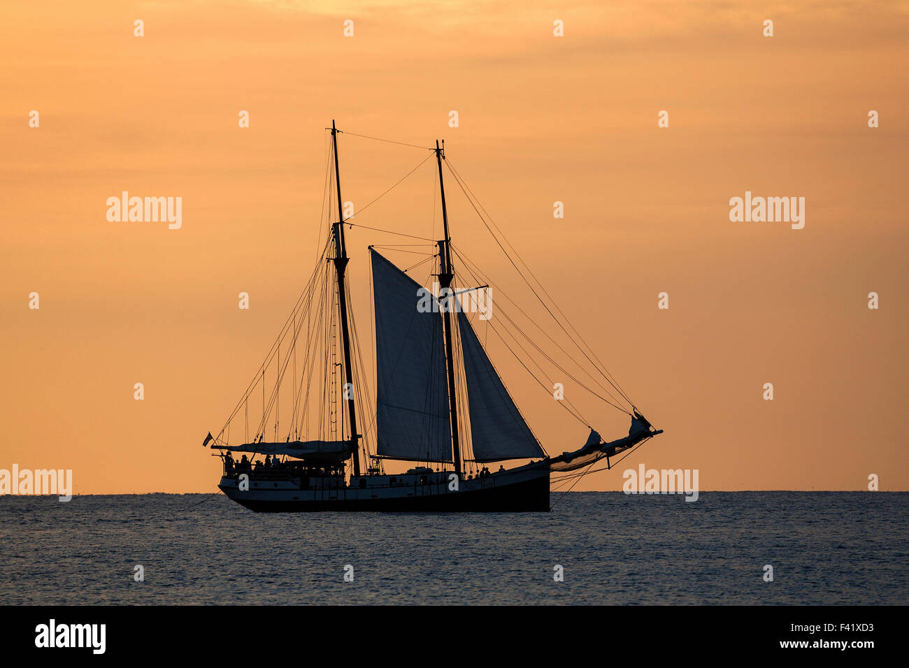 Barca a vela nella Baia di Beau Vallon di fronte a un cielo arancione, tramonto, Isola di Mahe, Seicelle Foto Stock