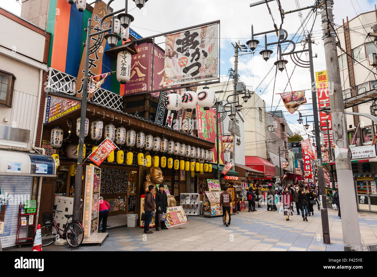 Osaka, Shinsekai, famosa area del centro cittadino, foreground, noodle bar con molti chochin, lanterne di carta e Billiken statua nella principale strada dello shopping. Ore diurne. Foto Stock