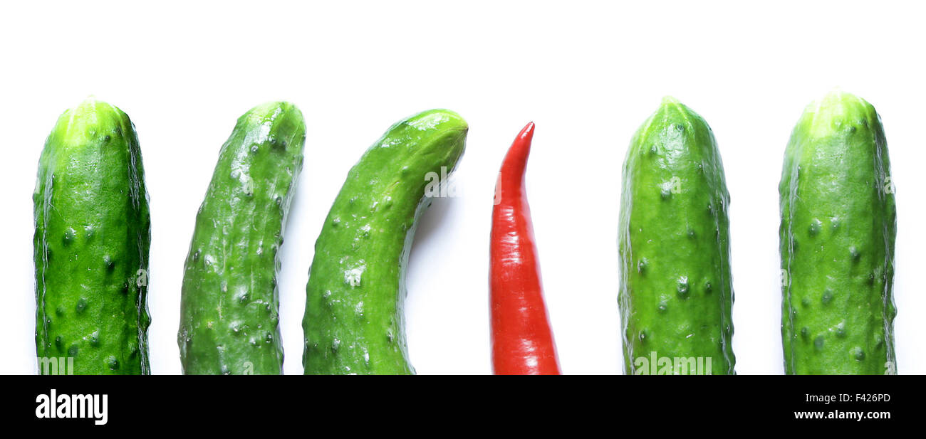 Cetrioli di verde con una red hot chili pepper in piedi fuori dalla folla Foto Stock