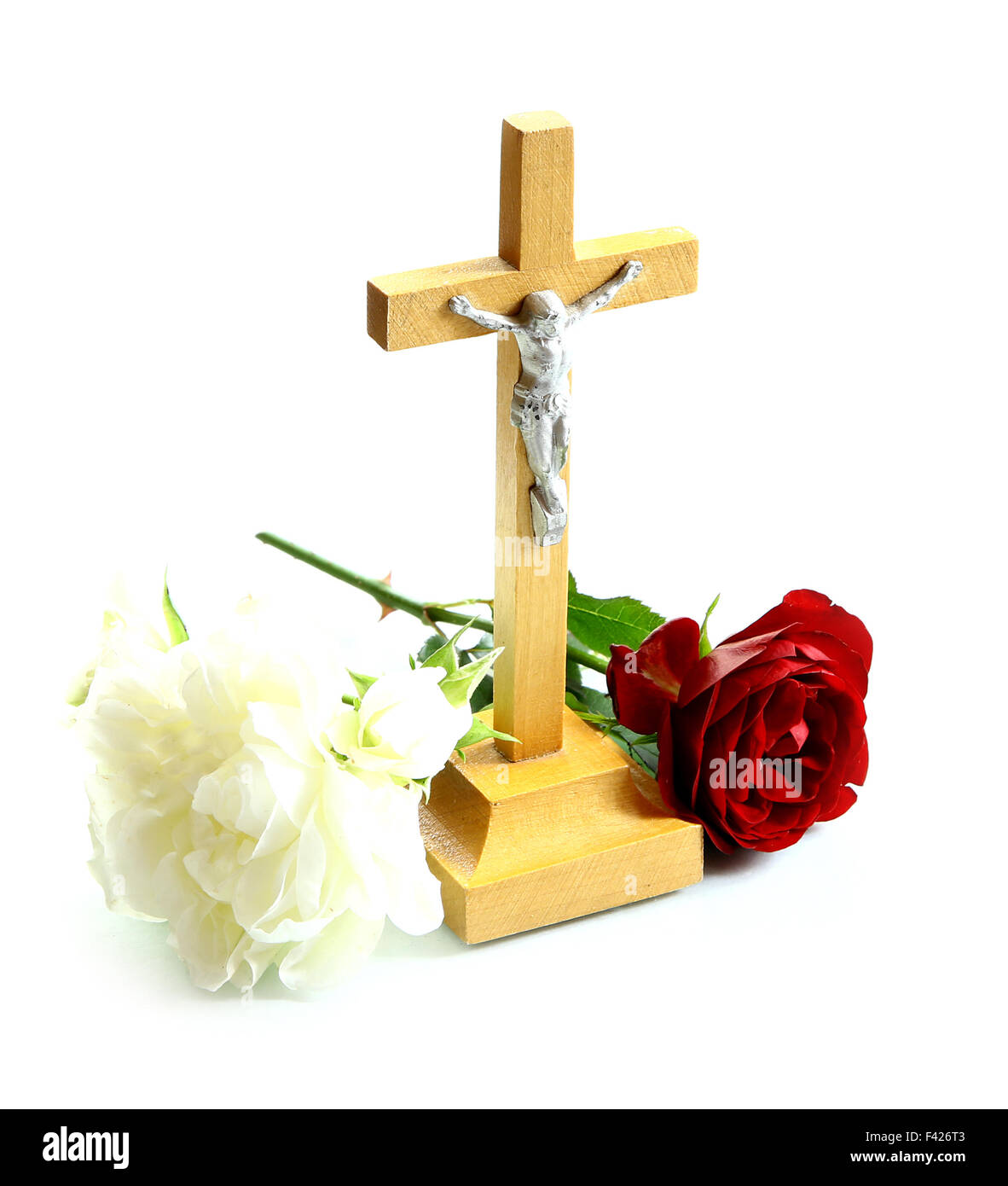 Molto semplice di legno santo crocifisso Gesù Cristo sulla croce lo sfondo bianco con rose bianche e rosse Foto Stock
