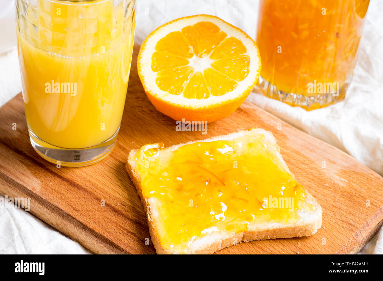 Sandwich con marmellata di arancia e un bicchiere di succo di frutta Foto Stock