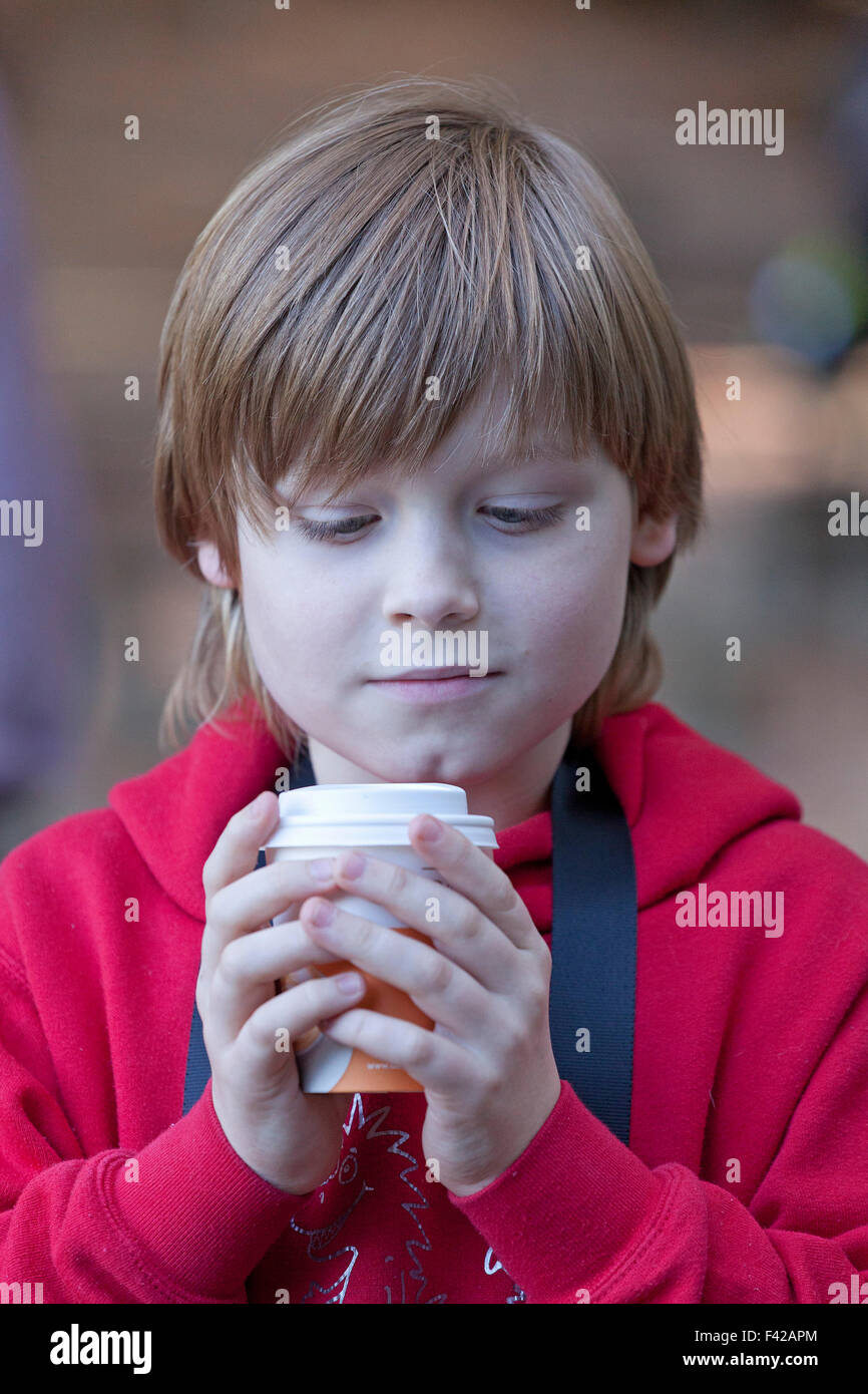 Ritratto di un giovane ragazzo con un bicchiere di carta in mano Foto Stock