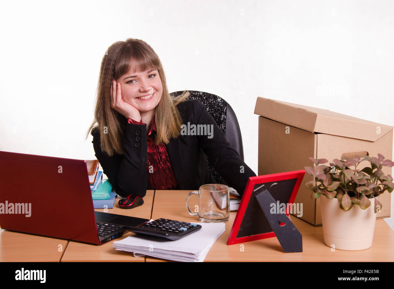 Ufficio sorridente dipendente seduto al tavolo Foto Stock