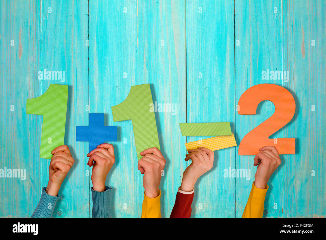 Le mani con la semplice equazione matematica contro blu parete in legno Foto Stock
