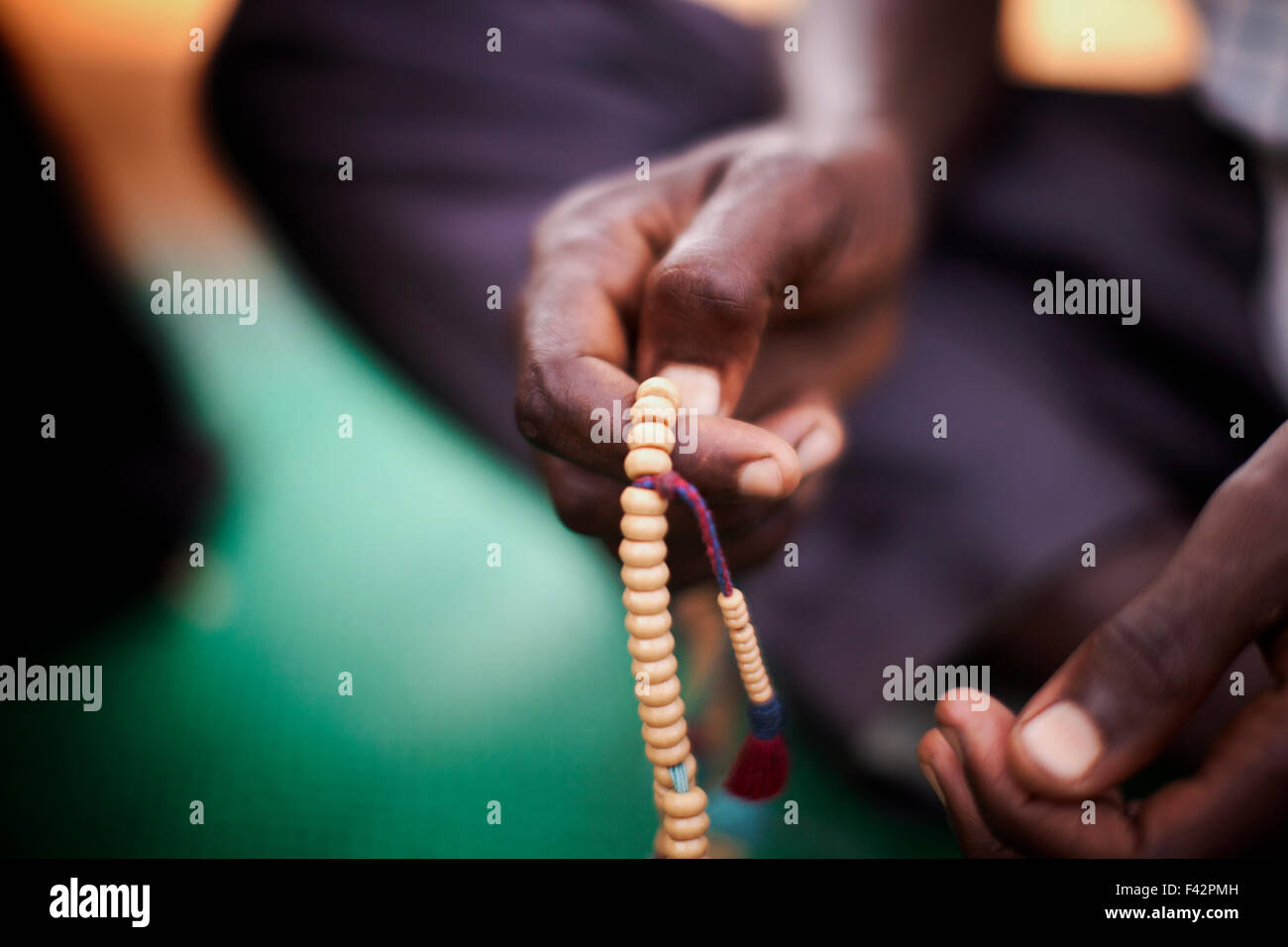 Un uomo dolcemente lascia il suo pollice scorrere sopra i talloni del suo tasbih come recita i versetti del Quaran, Bossangoa, Repubblica Centrale Africana Foto Stock
