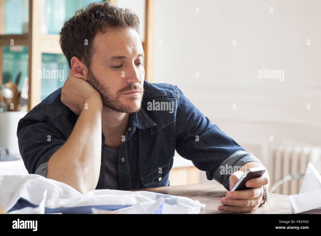 Uomo a casa utilizza lo smartphone Foto Stock