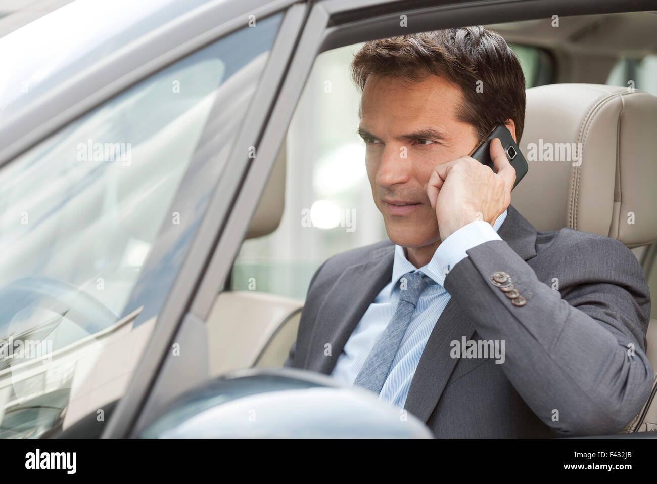 Imprenditore parlando al cellulare in auto Foto Stock