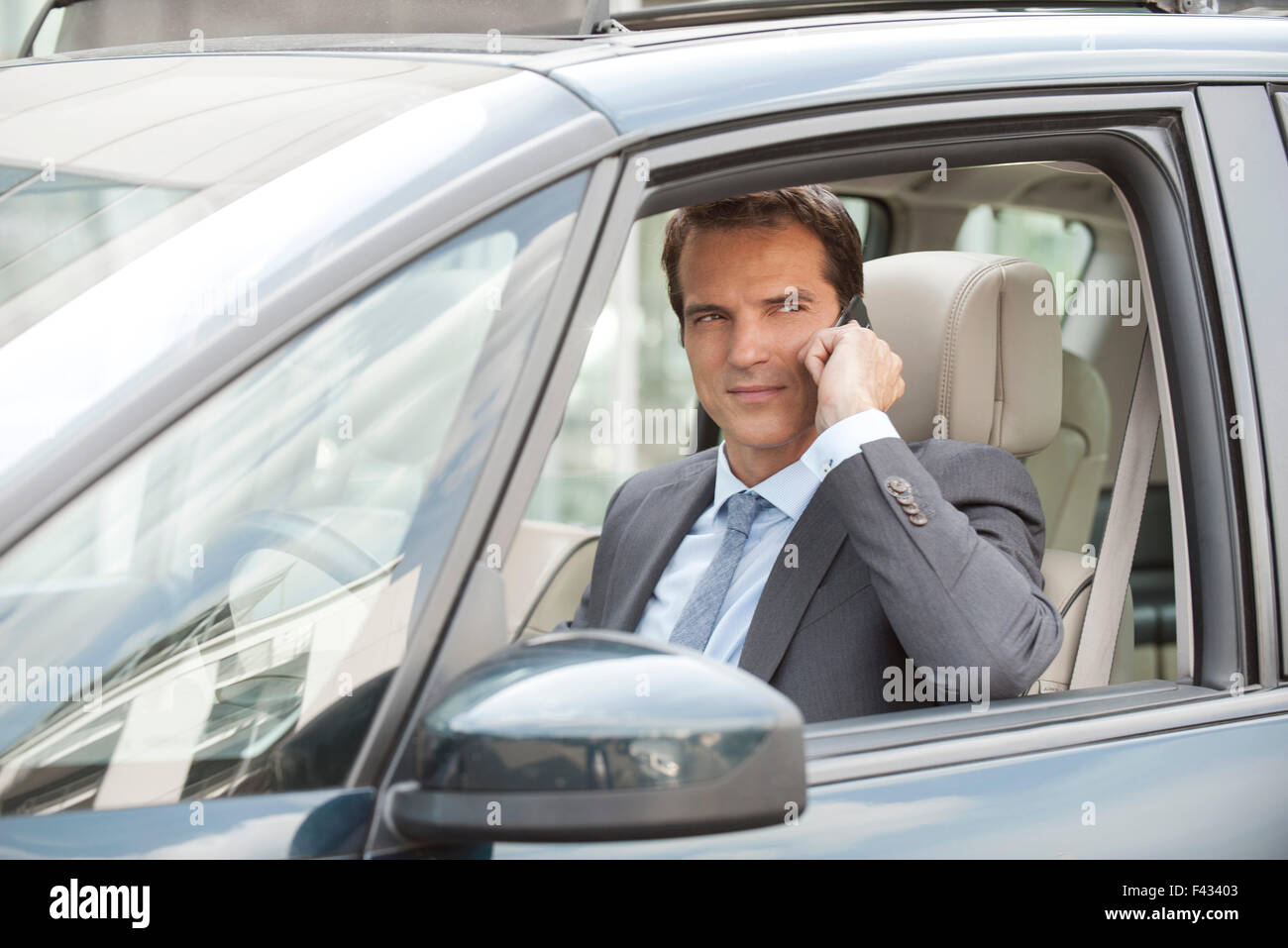 Imprenditore utilizzando il telefono cellulare mentre si guida auto Foto Stock