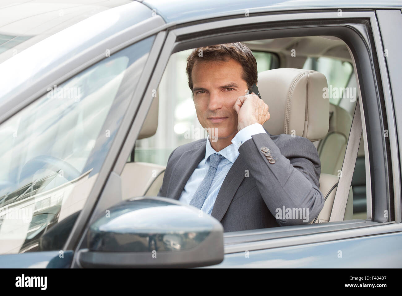 Imprenditore utilizzando il telefono cellulare mentre si guida auto Foto Stock