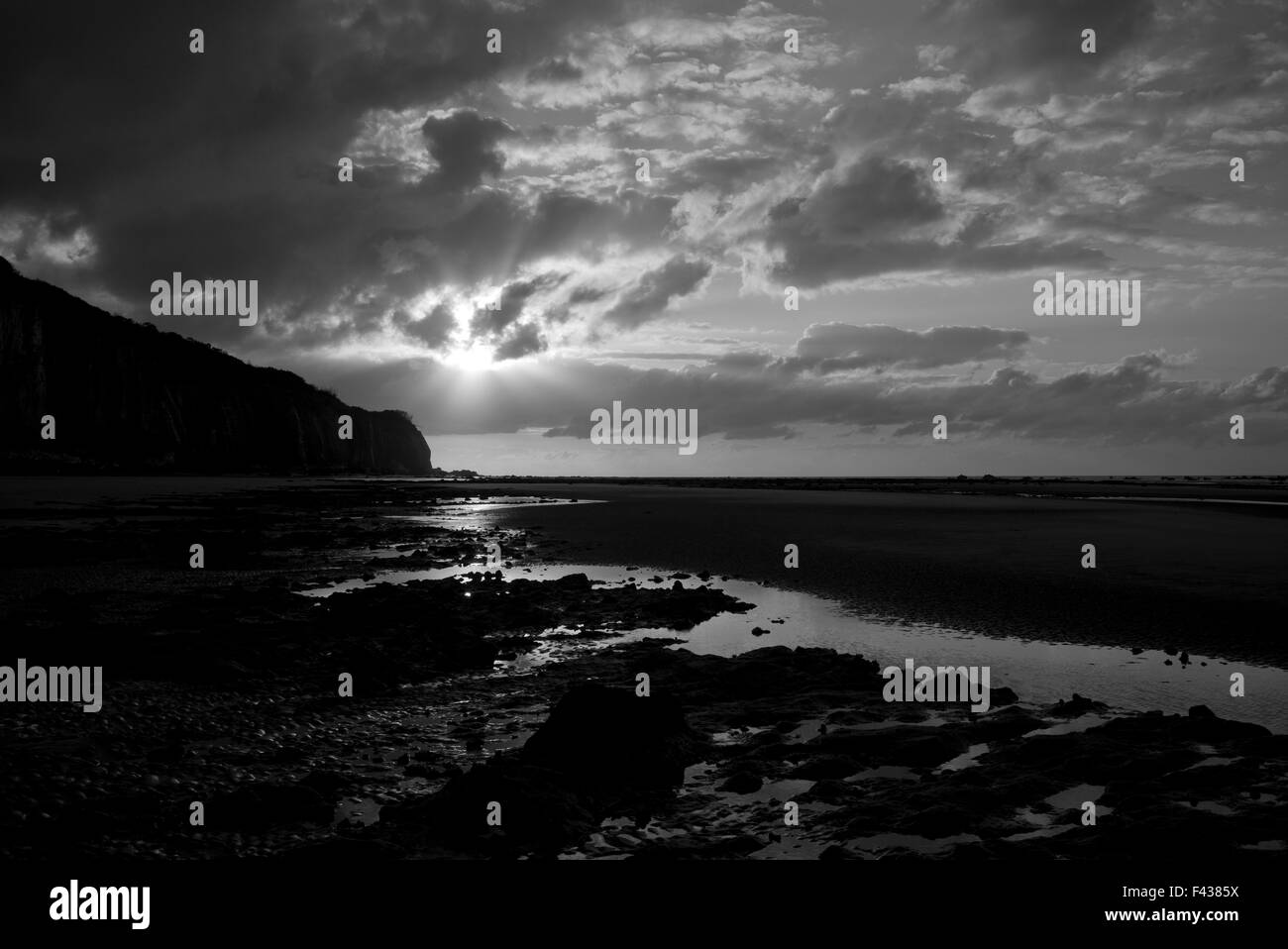 Tramonto sulla scogliera, la spiaggia e il mare, la bassa marea, in bianco e nero Foto Stock