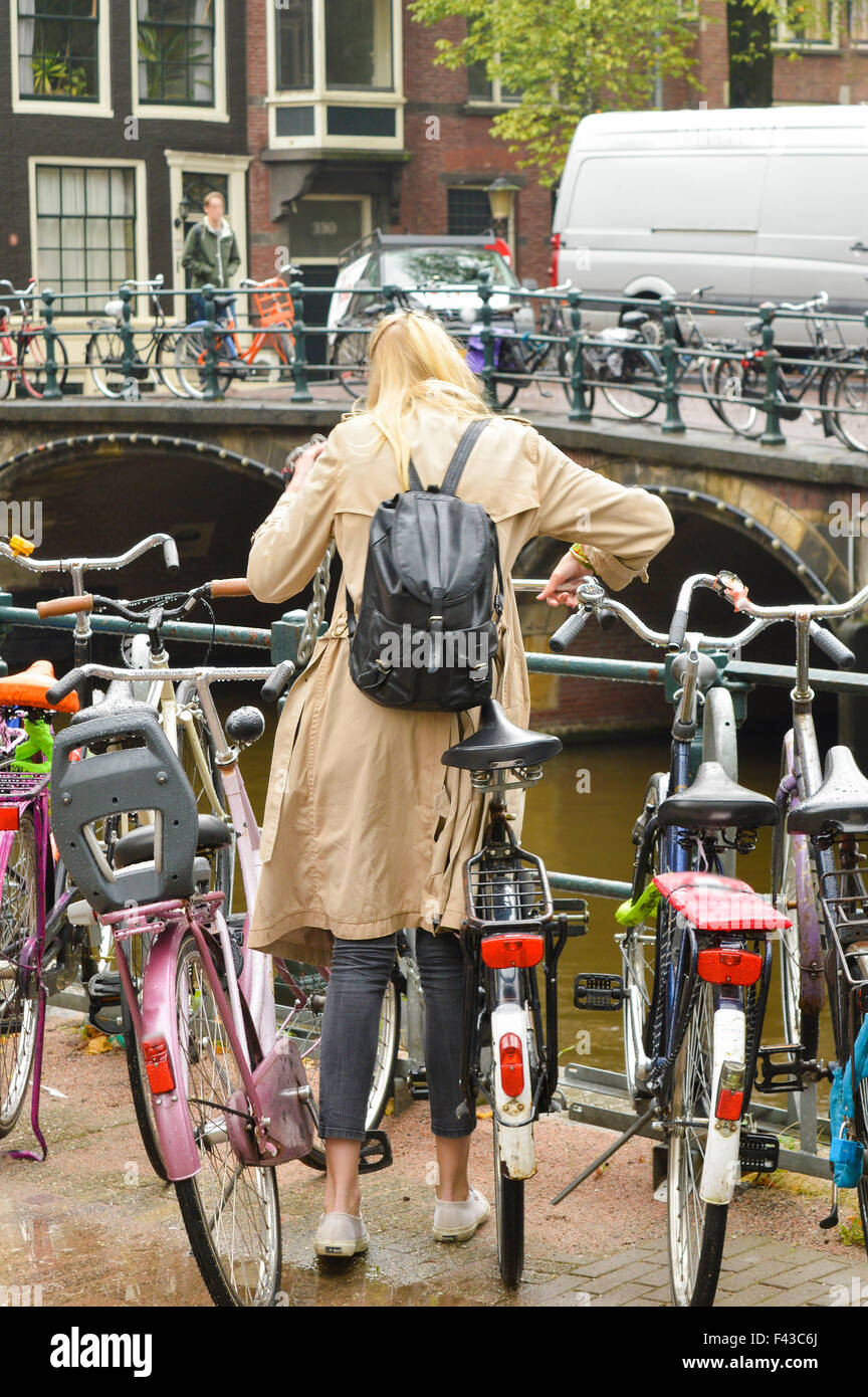 Donna a spostare il parcheggio biciclette di Amsterdam in un freddo giorno di autunno Foto Stock