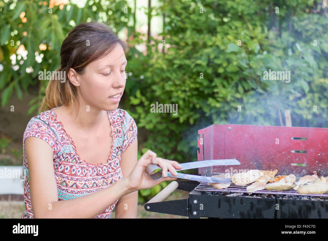 Bel giovane donna prepara barbecue nel cortile posteriore Foto Stock