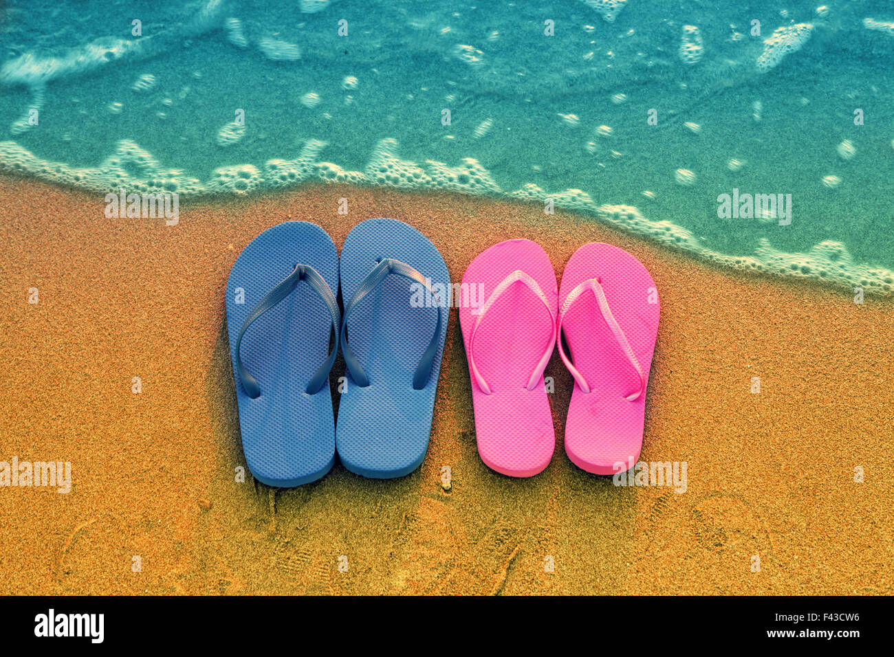 Romantica spiaggia scena. Maschio e femmina flpp flip sandali sulla spiaggia Foto Stock